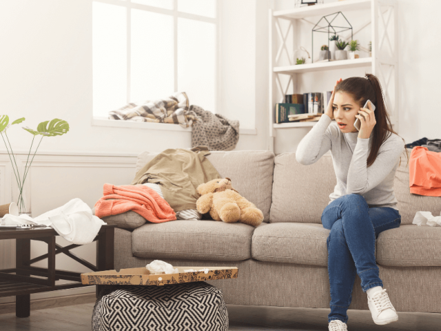 woman is on couch on the phone with a dirty, messy house.