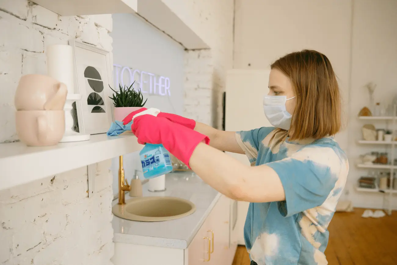 woman wearing mask while cleaning with commercial cleaner